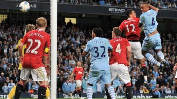 El jugador belga Vincent Kompany (der.) se eleva dentro del área del  Manchester United para marcar el gol que le daría el triunfo al City por 1-0.