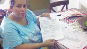 La dominicana María Pabón dice que le pagó a una compatriota que trabajaba en bienes raíces unos $5,000 para que le consiguiera un apartamento. En la foto, Pabón muestra copia del supuesto contrato falso de arrendamiento que recibió.