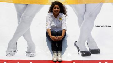 Natalia Juárez, candidata   a la legislatura federal, aparece detrás de un póster en el que se ven las piernas de dos mujeres.