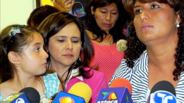 María Leonor (d.), una mexicana de 40 años y Carmen (atrás), una peruana de 44 años, acompañadas por sus hijos y la abogada Jessica Domínguez (centro), durante una rueda de prensa para pedir clemencia a Inmigración