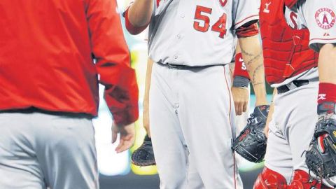 Ervin Santana (centro) devuelve la bola al mánager Mike Scioscia después de lanzar siete entradas ante los Meliizos.
