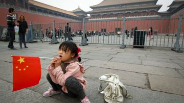 Una niña descansa frente a la Ciudad Prohibida en Pekín.