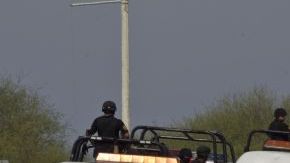 La policía federal escolta a los camiones de forenses con decenas de cuerpos, algunos de ellos mutilados, encontrados en una carretera en la ciudad de San Juan, cerca de Monterrey, México.