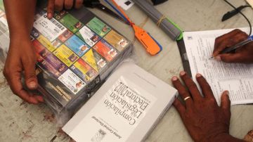Miembros de un colegio electoral dominicano revisan un paquete con votos.