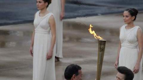 La Princesa Ana sostiene la antorcha con la flama olímpica que le entrega el presidente del Comité Olímpico Griego, Spyros Kapralos, en el Estadio Panatinaico.