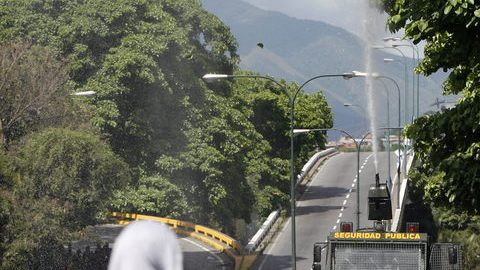 Familiares de reclusos escapan de gases lacrimógenos lanzados por la Guardia Nacional en los alrededores del centro penitenciario La Planta, en Caracas.