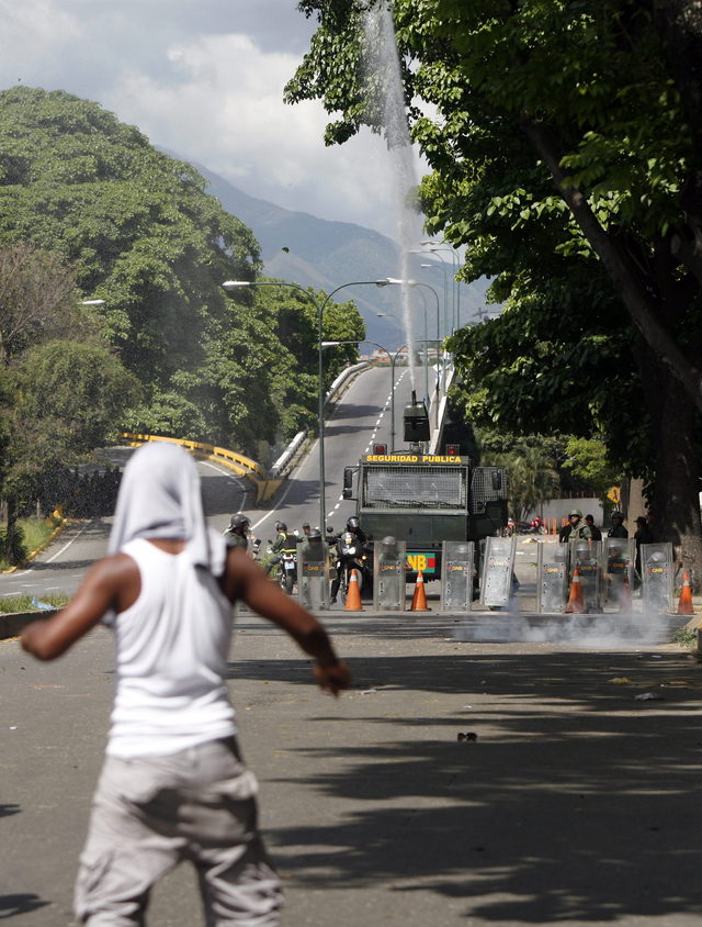 Familiares de reclusos escapan de gases lacrimógenos lanzados por la Guardia Nacional en los alrededores del centro penitenciario La Planta, en Caracas.