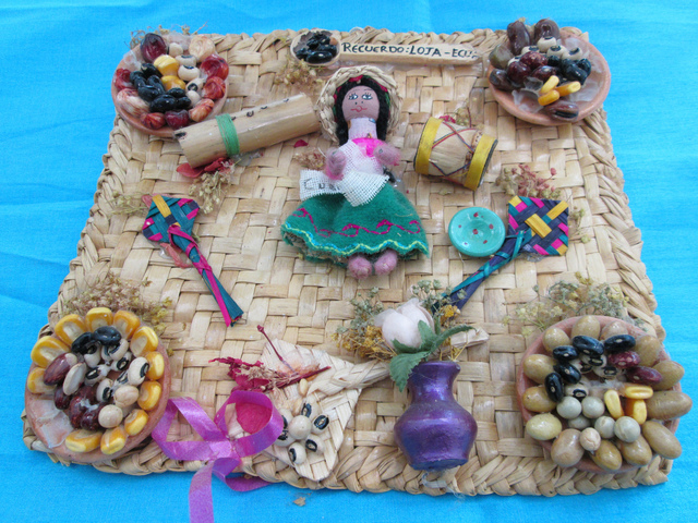 En el cuadro se ve una variedad de objetos típicos de la región de Loja, en Ecuador. Desde la típica campesina, como los alimentos característicos del área, sus flores  y otros productos artesanales.