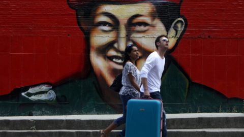 Una pareja camina junto a una imagen del presidente venezolano Hugo Chávez.