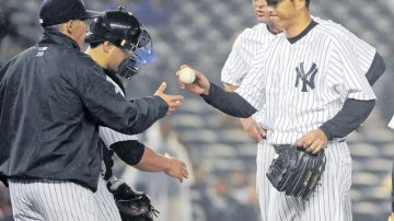 El pitcher japonés Hiroki Kuroda (der.) le entrega la bola al  manager Joe Girardi durante la sexta entrada de otro pobre juego de los Yankees.