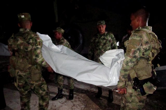 Miembros del Ejército  cargan uno de los doce cuerpos de un grupo de militares abatidos durante un combate con las FARC en Maicao, frontera común.