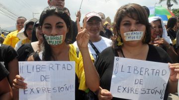 Periodistas y manifestantes marchan con la boca tapada con una cinta en la que se lee en español "Si hablo me muero" y pancartas que rezan "Libertad de expresión!" durante  una protesta en contra la violencia.