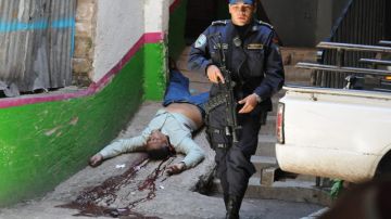 Un policía permanece junto al cuerpo de Francisco Pavón,  chófer del director de la Policía de Honduras, asesinado en Tegucigalpa  el jueves pasado.