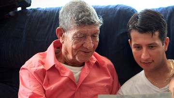 Tranquilino Castañeda muestra fotos de su pueblo natal a su hijo Oscar  Ramírez y a sus nietas Nicole y Andrea el 29 de mayo en    Framingham, Massachussetts.