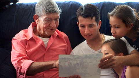 Tranquilino Castañeda muestra fotos de su pueblo natal a su hijo Oscar  Ramírez y a sus nietas Nicole y Andrea el 29 de mayo en    Framingham, Massachussetts.