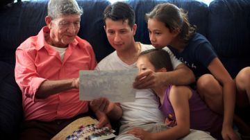 Tranquilino Castañeda muestra fotos de su pueblo natal a su hijo Oscar  Ramírez y a sus nietas Nicole y Andrea el 29 de mayo en    Framingham, Massachussetts.