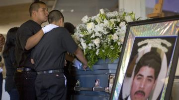 Miguel Garcia, de 17 años, mira hacia el cielo al lado de otros familiares frente al féretro que contiene los restos de su padre, Idelfonso (Alfonzo) Martínez.