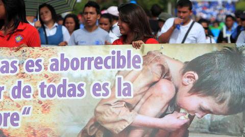 Estudiantes portan un cartel durante una marcha  para concienciar a la población sobre la necesidad de erradicar el hambre y la desnutrición infantil que sufren unos 300,000 niños en el pais centroaméricano.