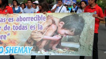 Estudiantes portan un cartel durante una marcha  para concienciar a la población sobre la necesidad de erradicar el hambre y la desnutrición infantil que sufren unos 300,000 niños en el pais centroaméricano.