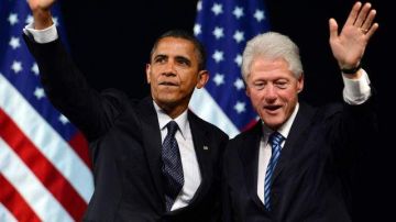 El presidente estadounidense, Barack Obama (i), y el expresidente Bill Clinton (d) saludan, durante una gira de recaudación de fondos para la campaña.