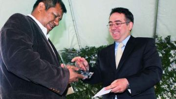 Alvarado (izq.) recibe la placa de manos de Héctor Villagra. Los 5 mil dólares que recibió irán al fondo en defensa de los jornaleros.