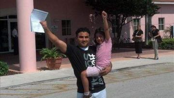 El guatemalteco indocumentado Marvin Corado alzando el brazo junto a su hija Madelyne.