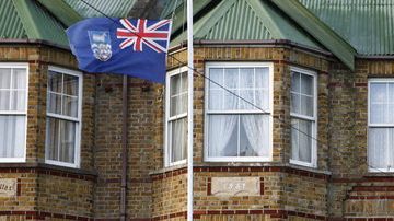 Una residente iza la bandera de las Islas Falkland frente a la puerta de su casa.