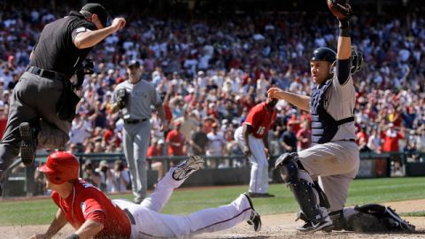 El receptor de los Yankees, Russell Martin (d) pone out a Tyler Moore, de los Nacionales de Washington, en el juego de ayer que ganó Nueva York  en 14 innings. Los 'Bombarderos' de El Bronx buscan hoy la barrida en la capital de la nación.
