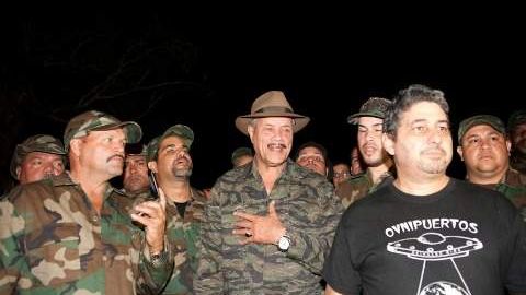El ufólogo Reinaldo Ríos, con camisa negra, quiere la ayuda del alcalde de Canóvanas, José "Chemo" Soto (con sombrero a lo "Indiana Jones") para atrapar a la criatura.
