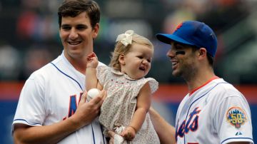 El quarterback de los Giants de Nueva York, Eli Manning (izq.) sostiene a su hija Ava  mientras posa con el tercera base de los Mets,  David Wright.