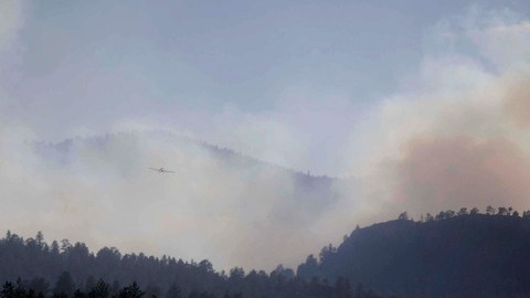 Un aeroplano vuela y atraviesa el humo del fuego de Springer cercano a Lake George, en Colorado.