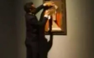 El pietaje muestra a un hombre vestido de negro que, en cuestión de segundos, rocía con aerosol la obra dejando la imagen de un toro y  la palabra “conquista” en el cuadro.