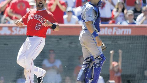 Albert Pujols celebra en home ante Matt Treanor luego de anotar carrera con sencillo de Mark Trumbo en la séptima entrada.