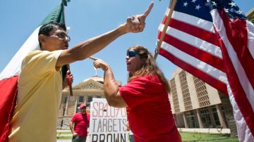 Andy Hernández, quien carga la bandera mexicana, y Allison Culver, con la insignia de EEUU, discuten sobre la SB1070 frente al edificio federal en Phoenix, Arizona.