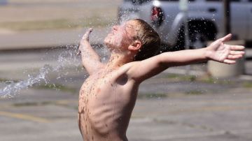 Un niño se refresca con agua en un campamento de verano en Moline, Illinois.