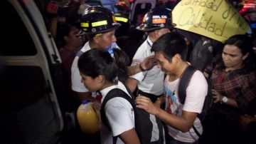 Varios estudiantes suben a una ambulancia después de evacuar las instalaciones de un instituto en el que las fuerzas de seguridad recuperaron el control.