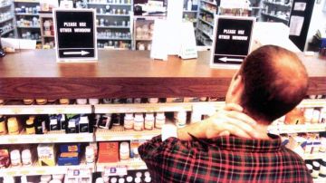 Un hombre frente al mostrador de una farmacia en Nueva York escoge una medicina para su compra.