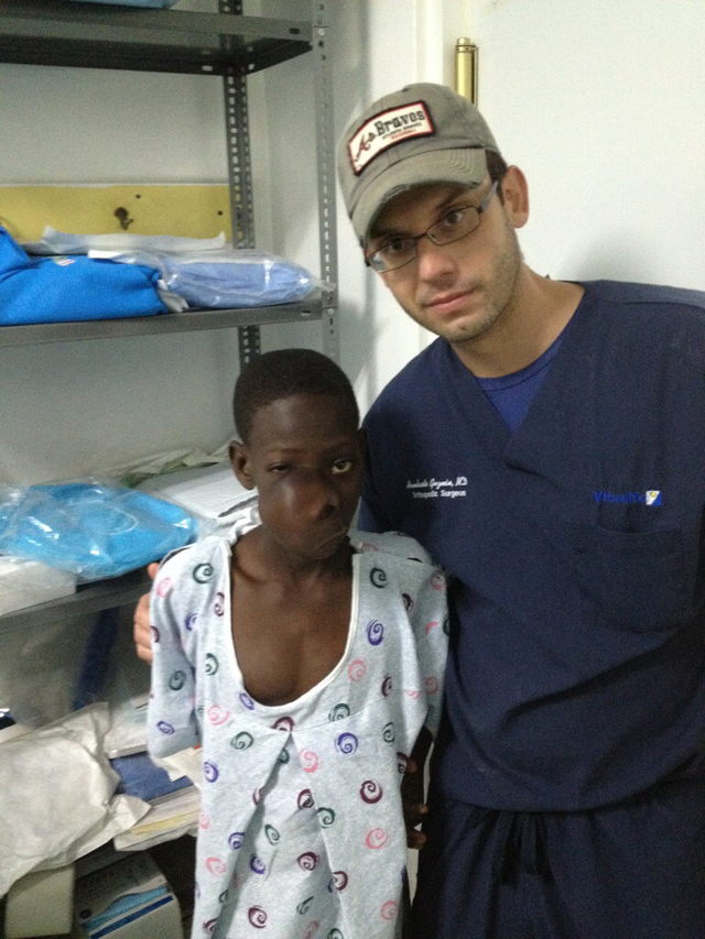El presidente de la Fundación Haití se Pone en Pie, Humberto Guzmán, posando al niño haitiano Gerilon Mondesir antes de extirparle un enorme tumor en la cara.