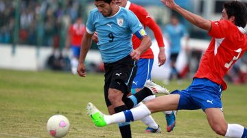 El uruguayo Luis Suárez (izq.), disputa el balón con el jugador de Chile, Enzo Andía, en el duelo de ayer en Montevideo.