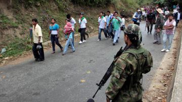 Indígenas pasan frente a un rebelde de las Fuerzas Armadas Revolucionarias de Colombia en las afueras de Toribío, al sur de Colombia.