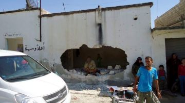 Varias personas observan los daños registrados tras un ataque en la localidad siria de Tremseh, provincia de Hama, Siria, ayer.