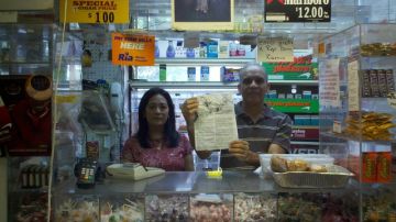Los bodegueros Altagracia Aristy y Pablo Ureña muestran la orden de desalojo que los obligará a cerrar su negocio en Tremont, tras 18 años de trabajo.