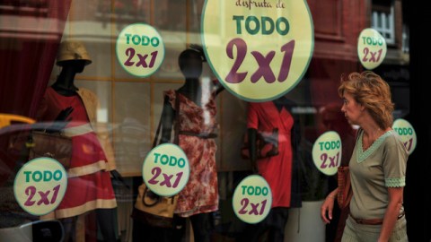 Una mujer pasa por una tienda de Pamplona (al norte de España), donde se anuncian rebajas.