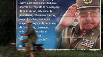 Un campesino pasea en bicicleta junto a un cartel con la imagen del presidente  Raúl Castro en la occidental provincia de Artemisa, Cuba.