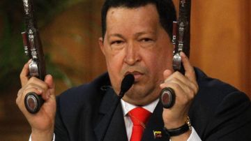 Hugo Chávez sostiene dos pistolas que pertenecieron a Simón Bolívar  durante un acto donde el mandatario desveló una imagen digitalizada del rostro de Bolívar que aparece en círculo.