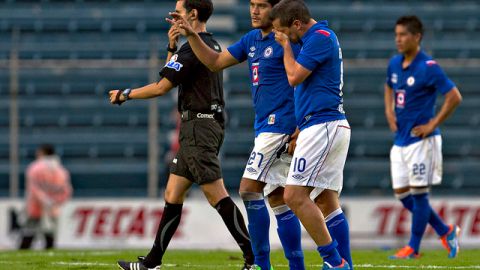 Christian Giménez abandona el campo con la mano en el rostro para cubrir su gesto de dolor mientras Javier Orozco lo consuela.
