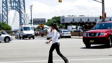 En la foto del 10 de julio, una mujer habla por celular mientras cruza una intersección cerca al puente George Washington, en Fort Lee, Nueva Jersey, donde una ordenanza estipula multas para los peatones que lo hagan, por considerarlo ilegal.