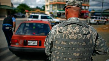 Mientras un policía pide los papeles al conductor de un carro, un militar presta vigilancia en una calle de San Juan donde ha aumentado la criminalidad.
