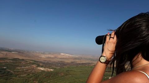 Una mujer israelí se ve usando  unos prismáticos desde la región de Bukata, en los Altos del Golán, Israel, en la frontera con Siria.