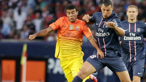 El delantero del PSG, Zlatan Ibrahimovic, conduce el balón ante la  marca del jugador del Barcelona, Rafinha Alcántara.